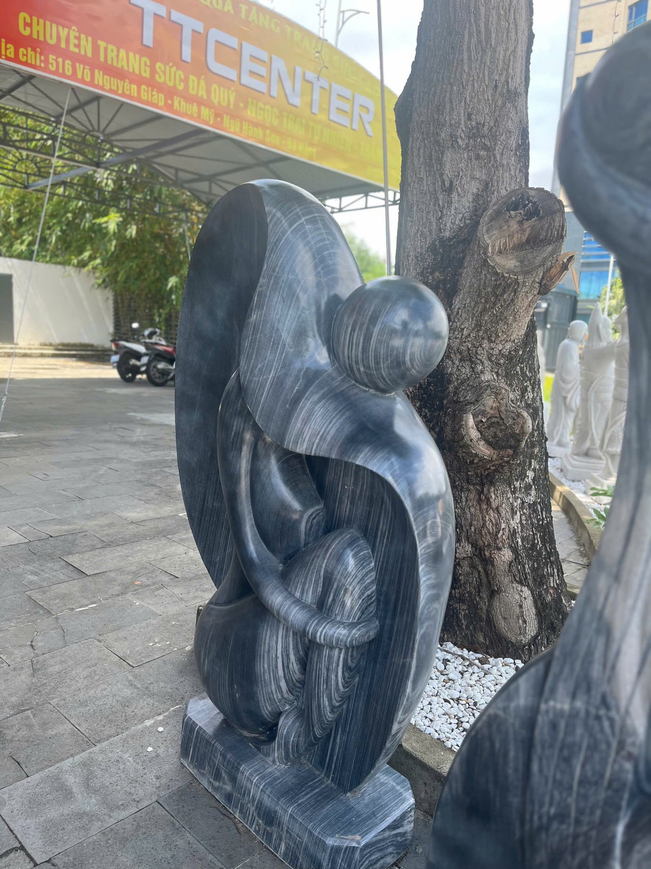 A HANDCRAFTED STONE SCULPTURE OF A GIRL, CARVED FROM A SINGLE BLOCK OF BLACK MARBLE NATURAL STONE, ITS ANTIQUE CHARM IS SURE TO CAPTIVATE ATTENTION, MAKING IT A STUNNNG SĐITION TO ANY GARDEN OR RESORT 