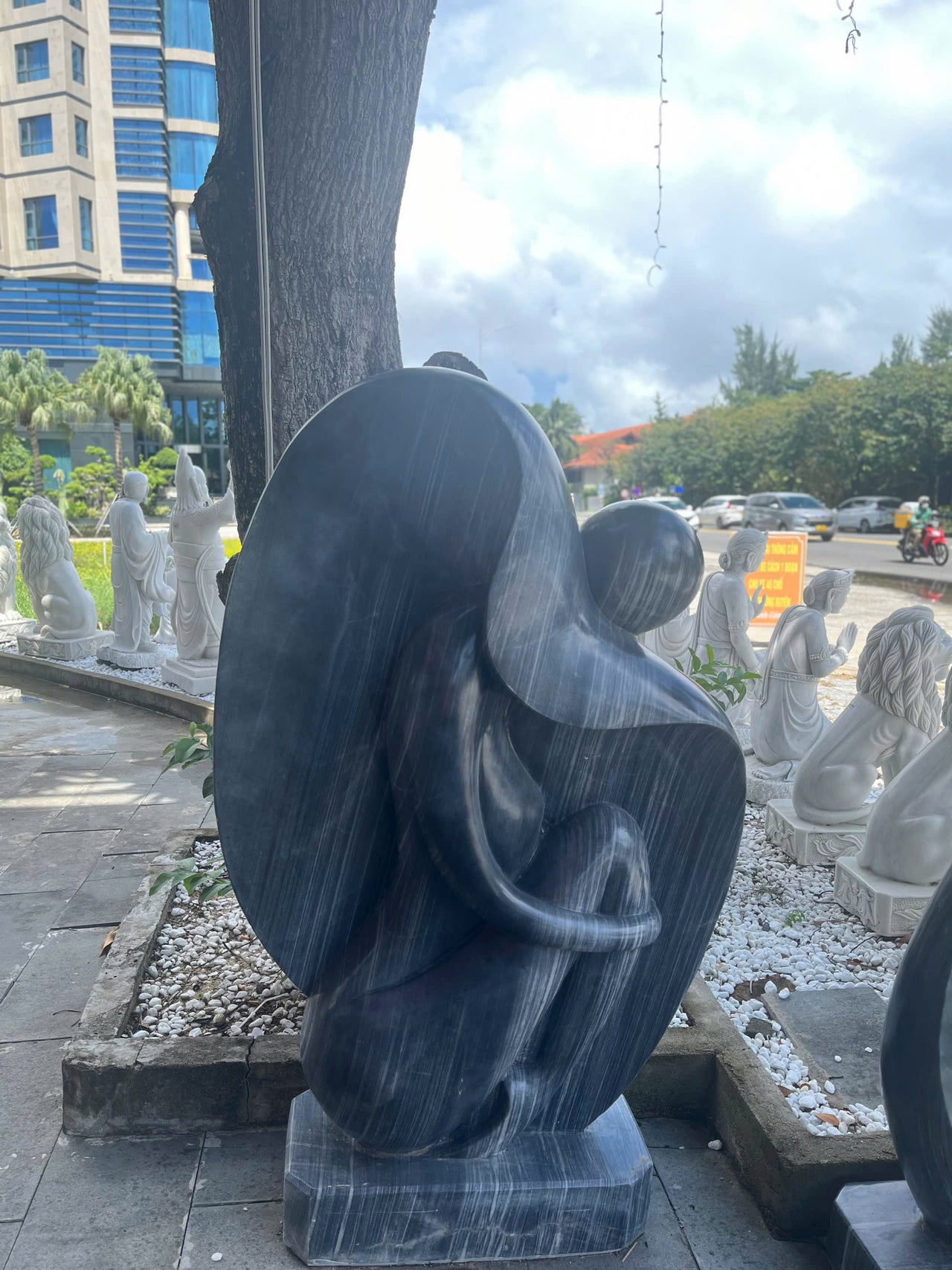 A HANDCRAFTED STONE SCULPTURE OF A GIRL, CARVED FROM A SINGLE BLOCK OF BLACK MARBLE NATURAL STONE, ITS ANTIQUE CHARM IS SURE TO CAPTIVATE ATTENTION, MAKING IT A STUNNNG SĐITION TO ANY GARDEN OR RESORT 